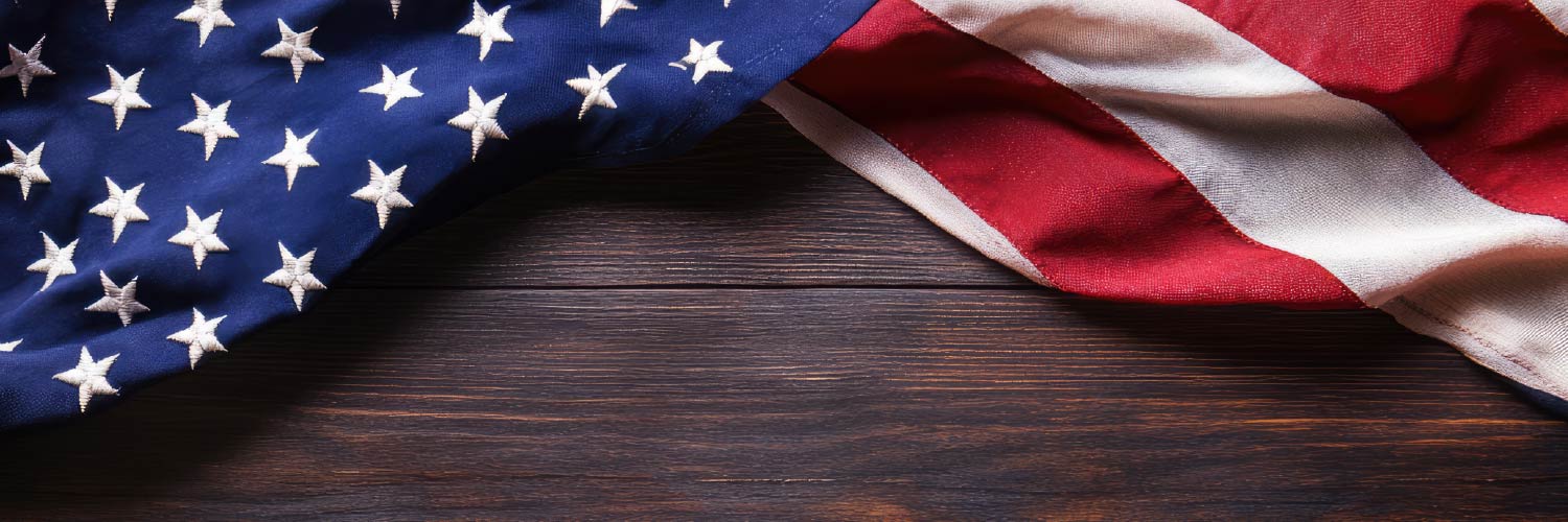 An American flag draped or displayed against a rustic wooden background, highlighting the texture of the wood and the flag's bold red, white, and blue colors